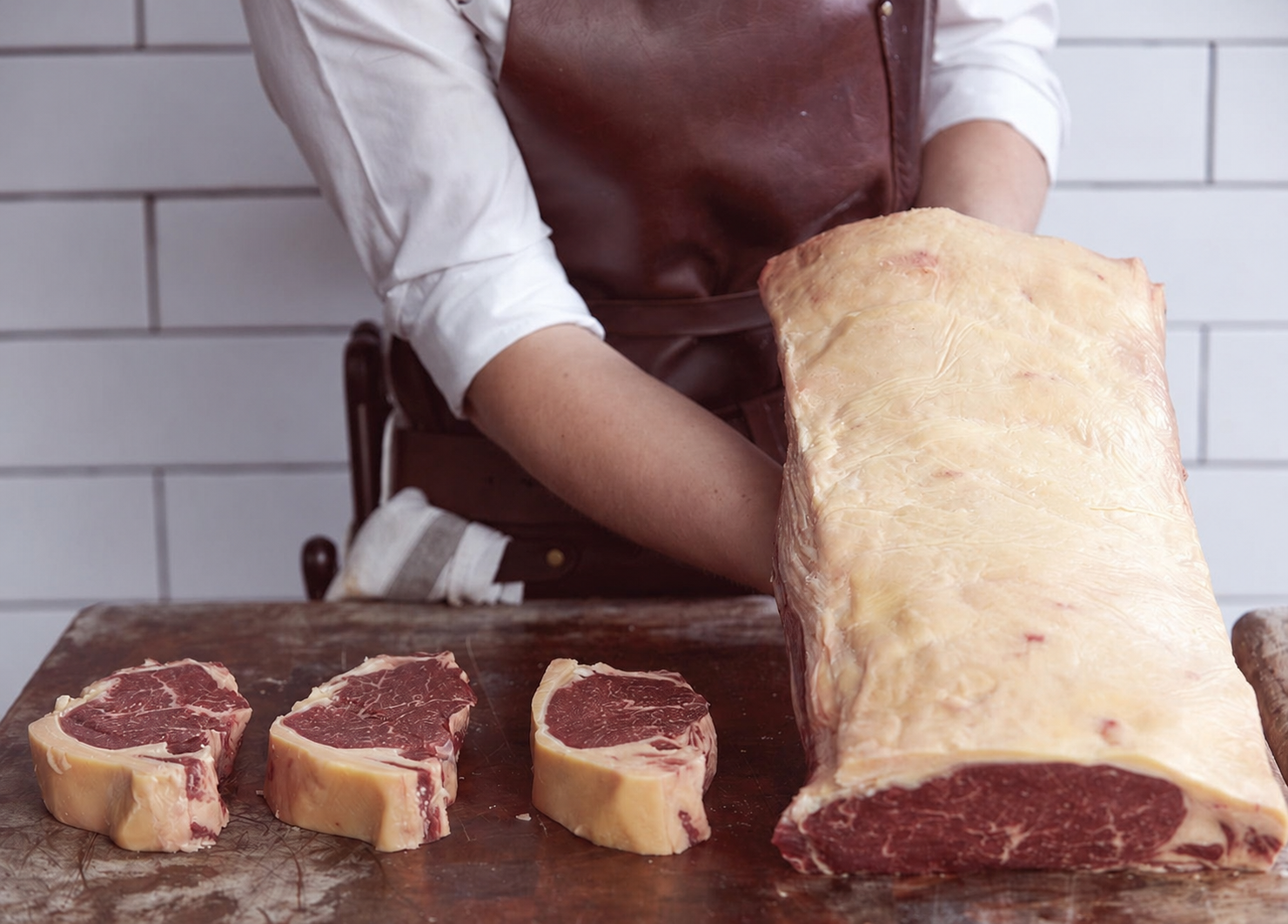 Galician-style beef — butcher with aged steaks on cutting board