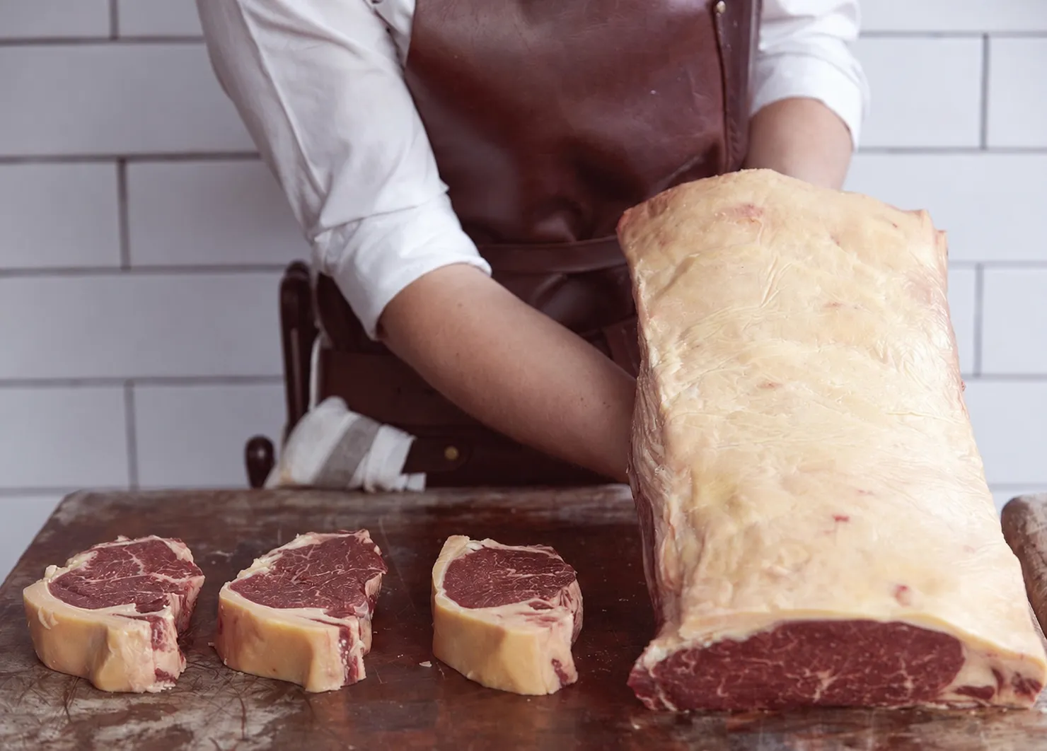 Galician-style beef — butcher with aged steaks on cutting board